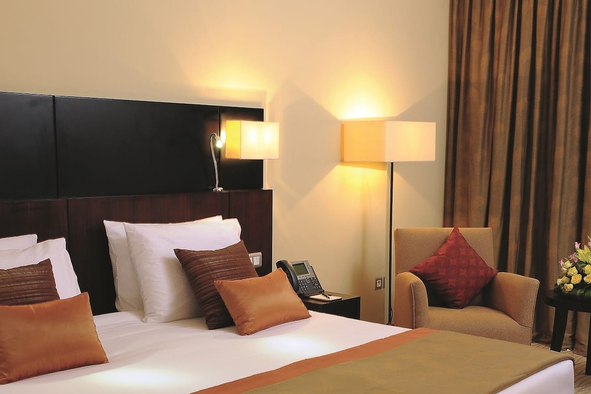 Une chambre d’hôtel avec un grand lit, un bureau avec un téléphone, une chaise et une lampe.
