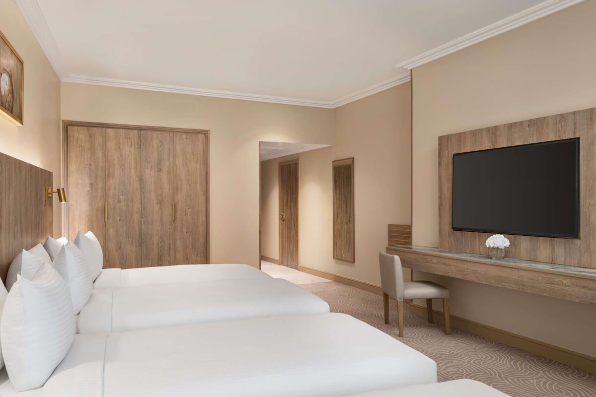 Een hotelkamer met een groot bed, een bureau, een televisie en een kledingkast.