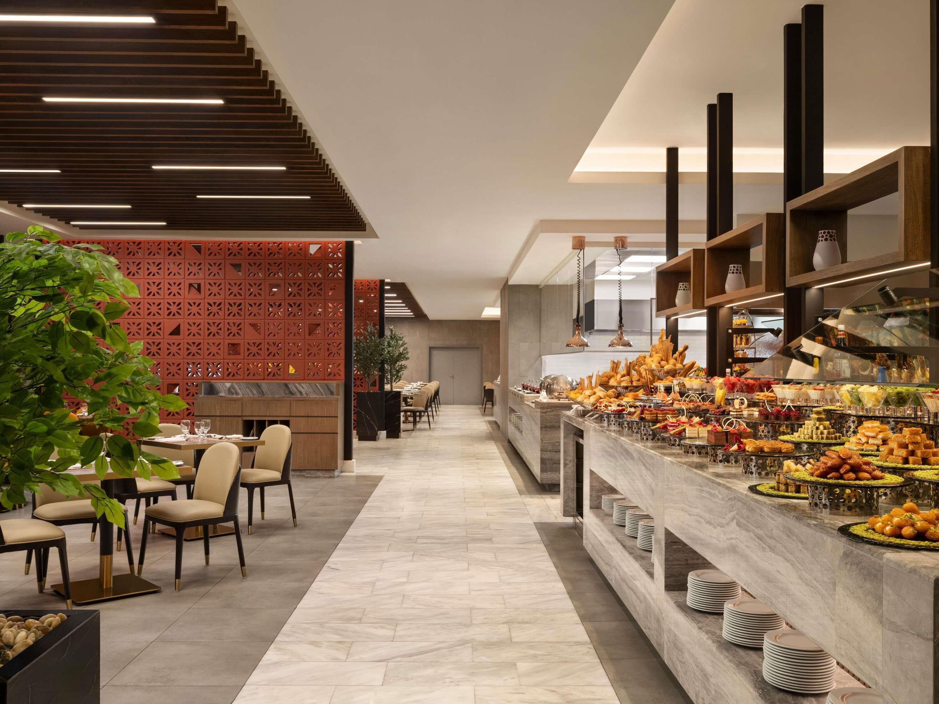 Un hall d’hôtel moderne doté d’un buffet, d’un espace salon et de plantes décoratives.