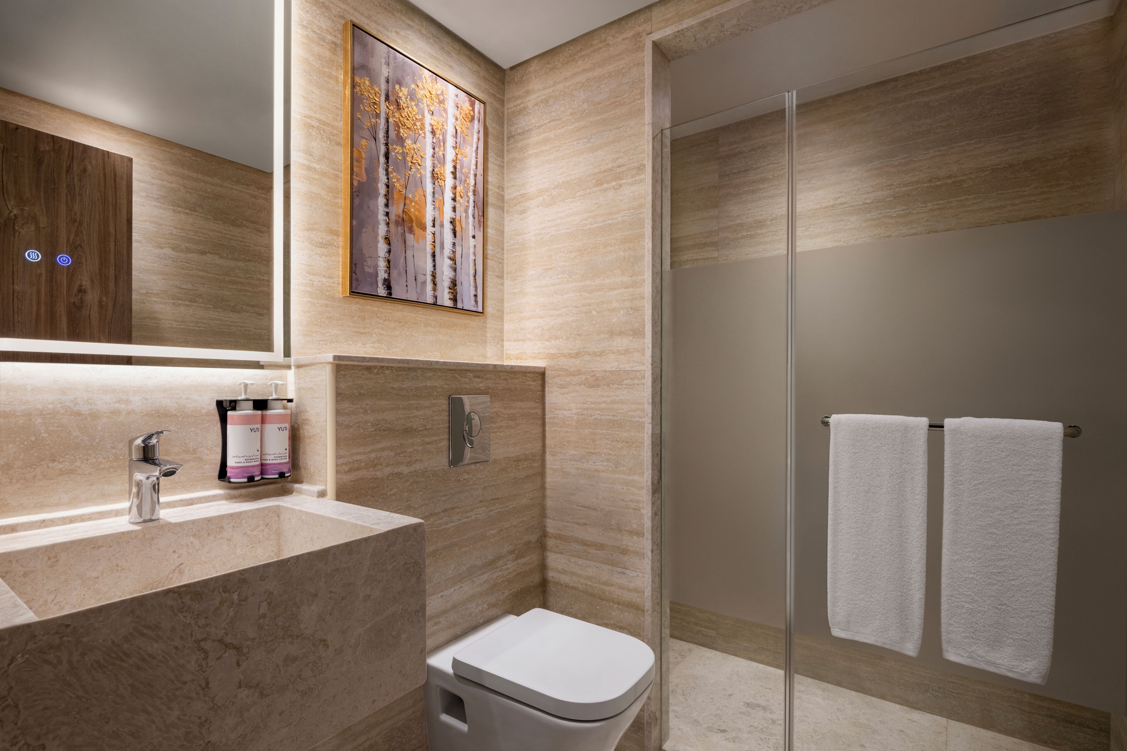 A modern bathroom with a marble sink, a toilet, a glass shower enclosure, and a towel rack.