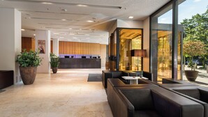 Een moderne lobby met een receptiebalie, een zithoek en grote ramen.