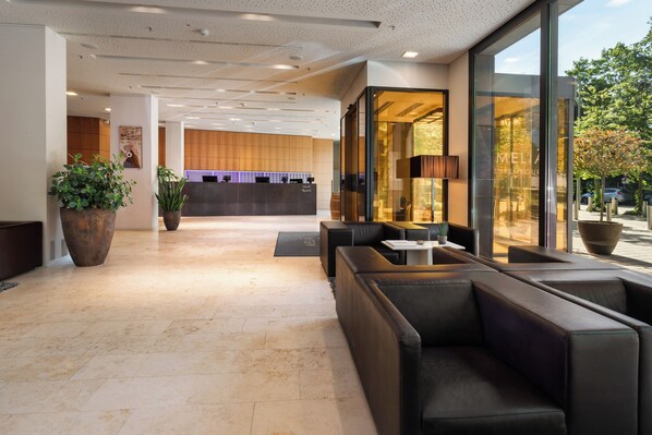 Een moderne lobby met een receptiebalie, een zithoek en grote ramen.