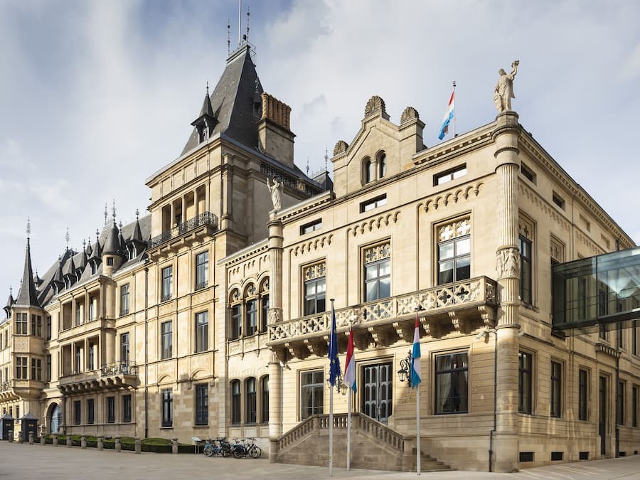 A historic building with ornate architecture, multiple flags, and a prominent statue on the roof.