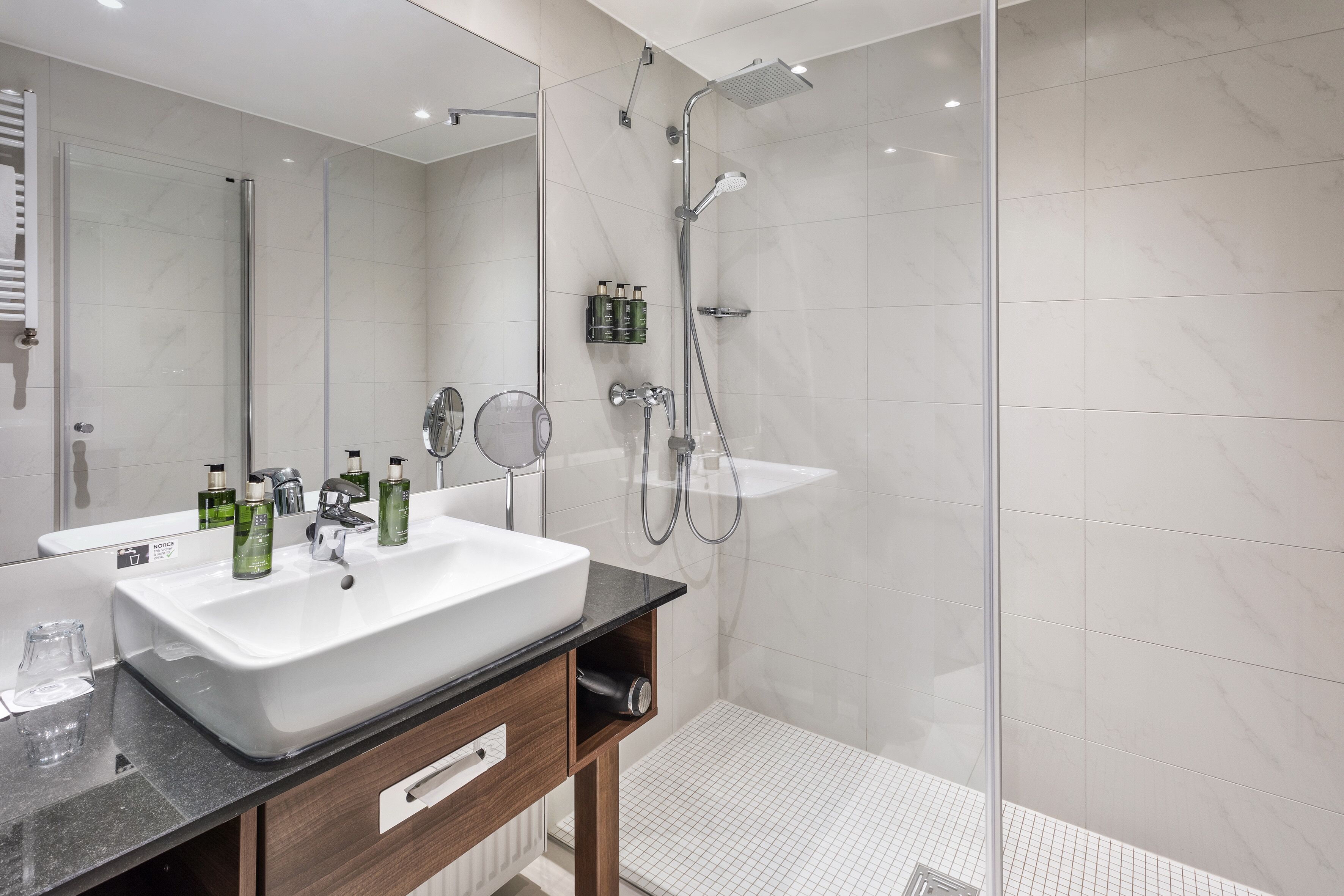 A modern bathroom with a large sink, mirror, and shower.