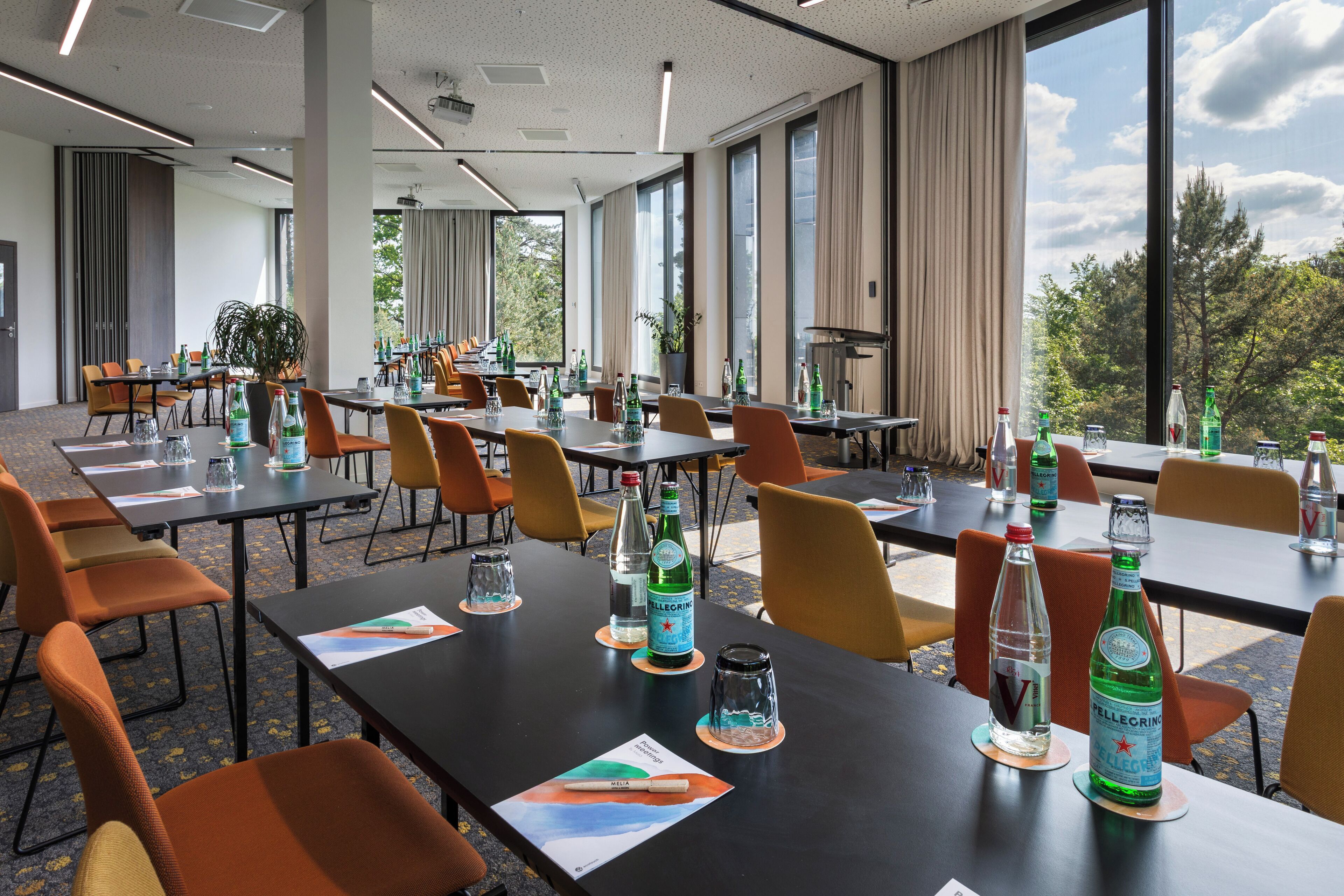 A conference room with tables, chairs, and bottles of Pellegrino water.