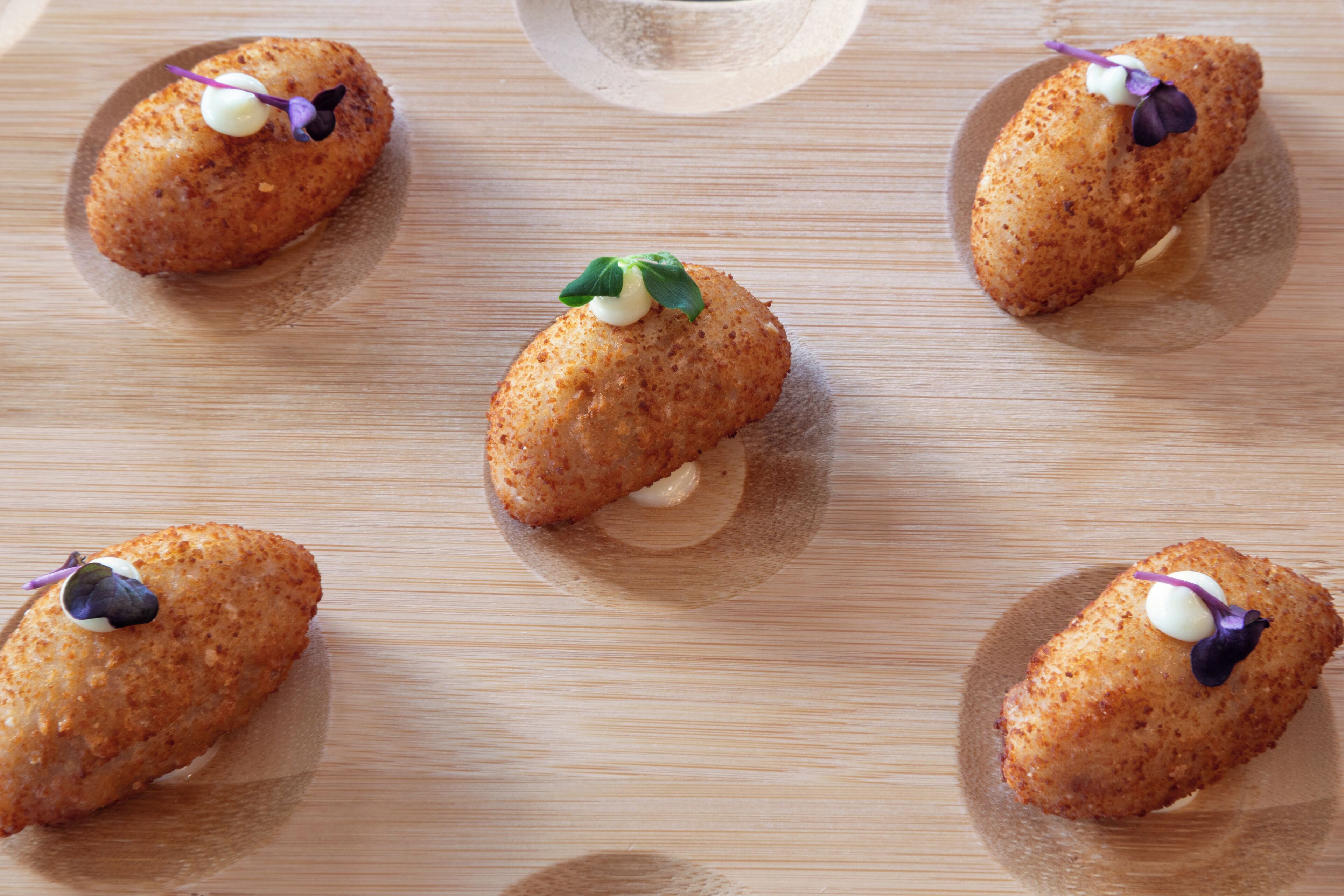 Five croquettes on a wooden board.
