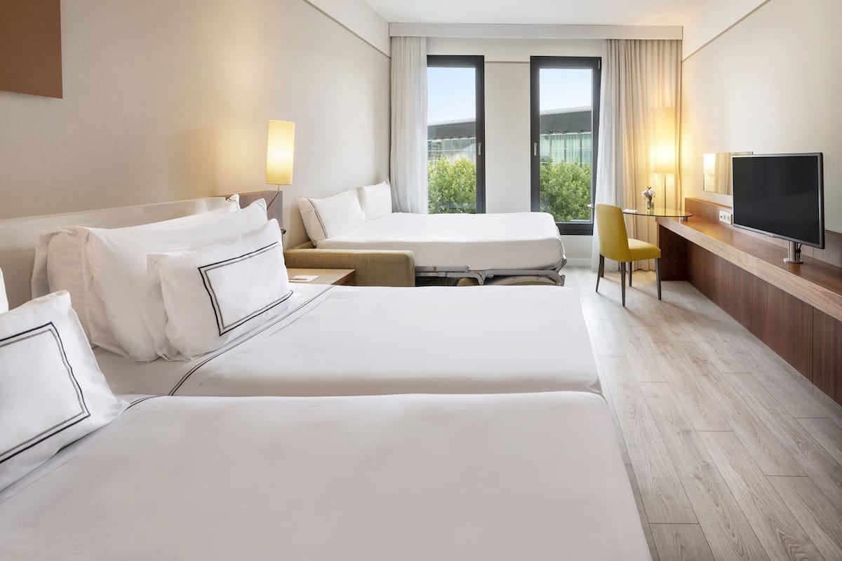 Una habitación de hotel con dos camas, un escritorio, una silla y un televisor.