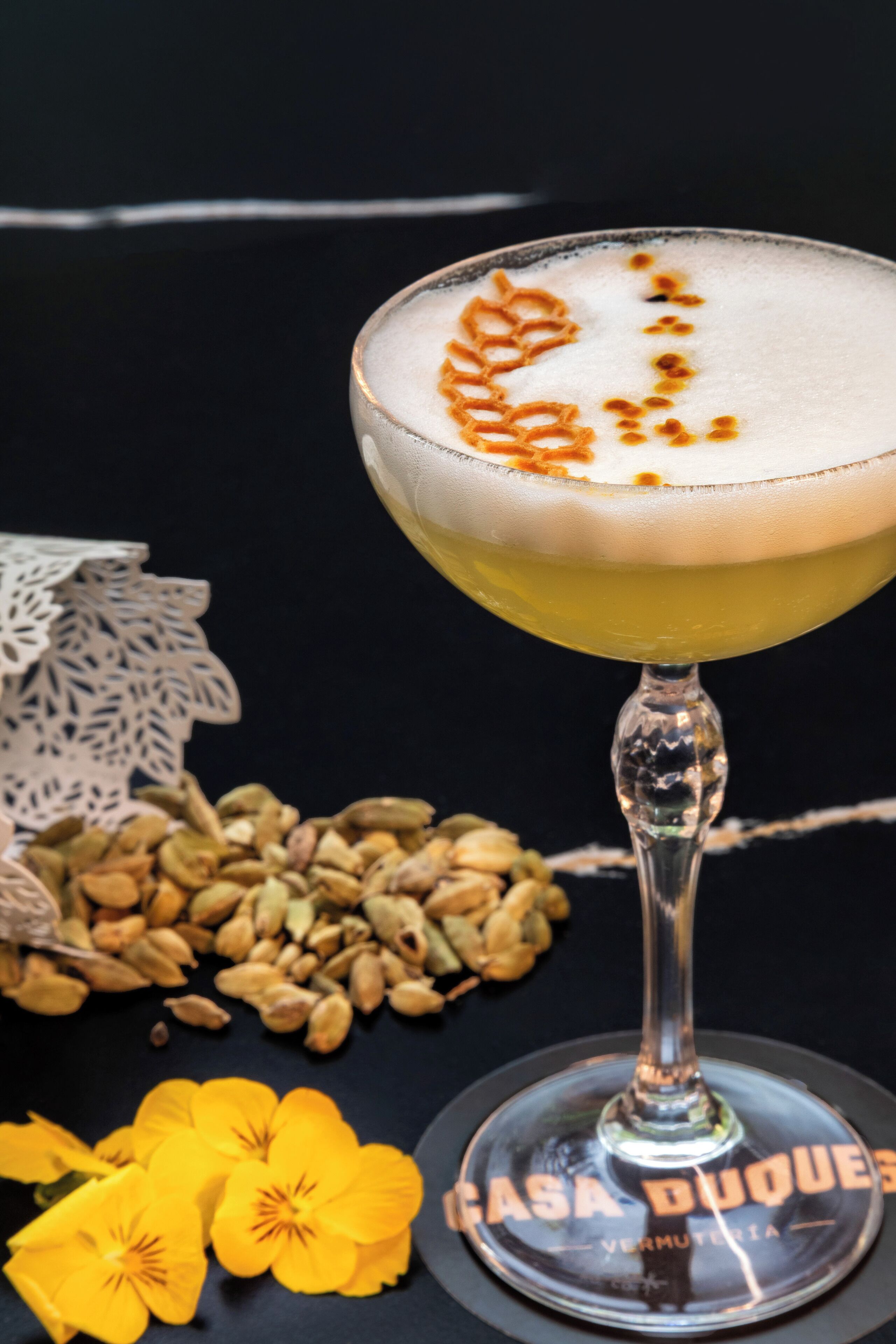 Un vaso de cóctel con un diseño espumoso decorativo, sobre un posavasos con texto.