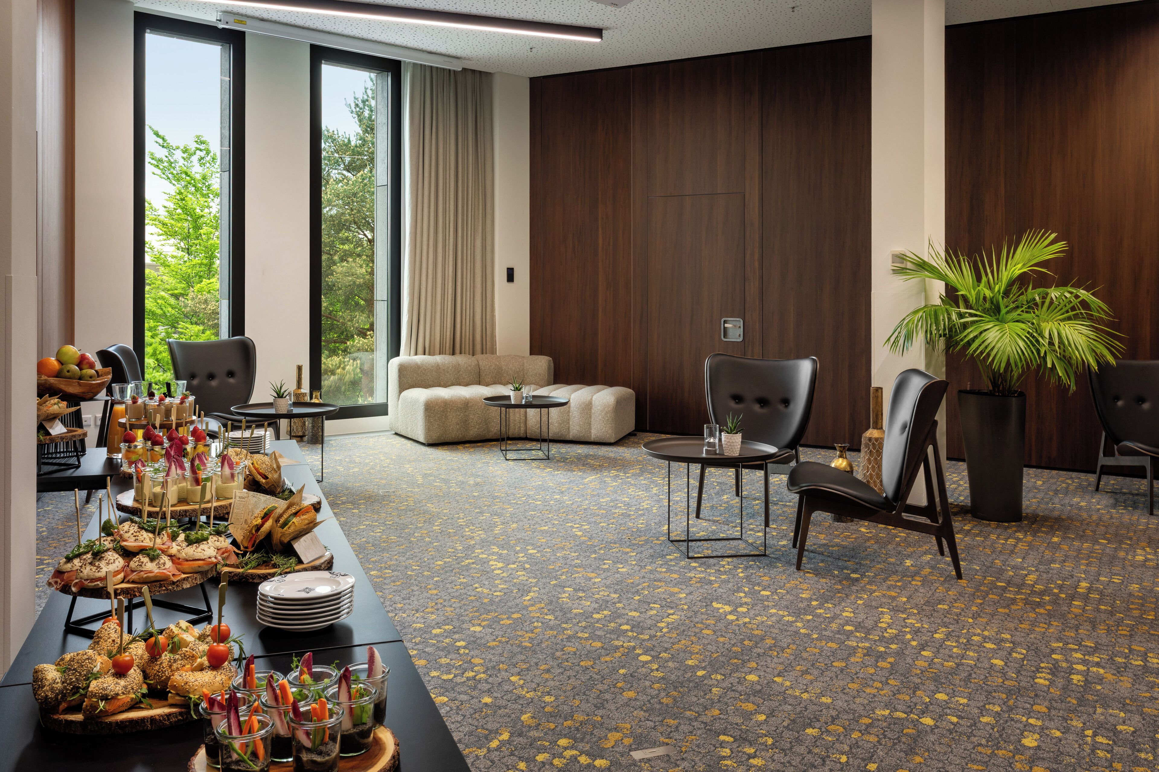 A conference room with a long table set for a buffet, a sofa, and two chairs.