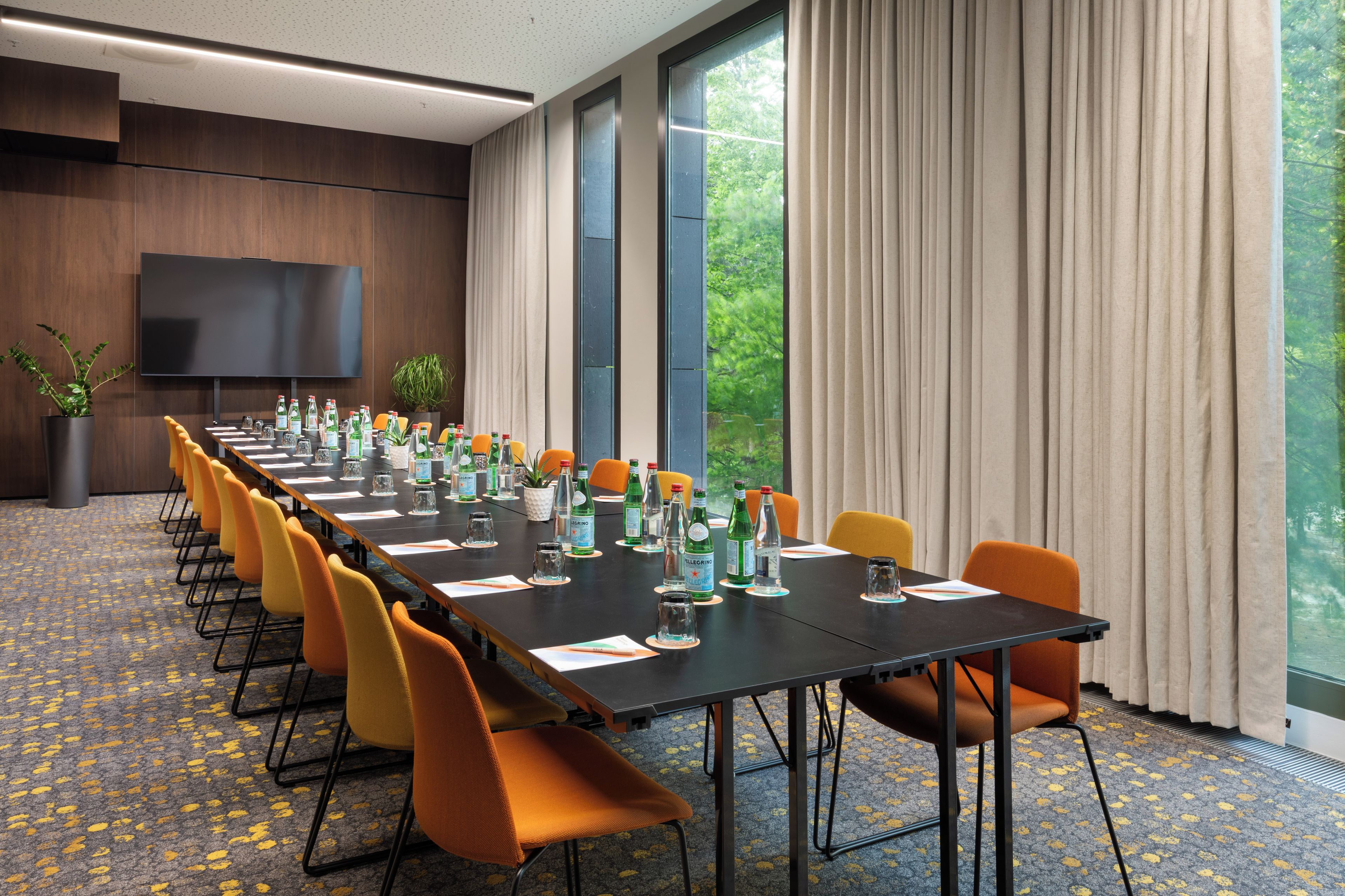 A conference room with a long table, multiple chairs, and a television screen.
