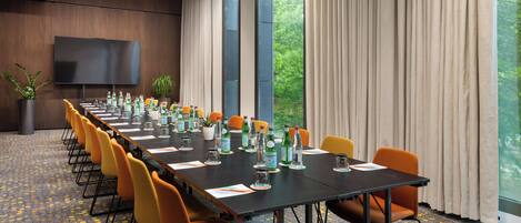 A conference room with a long table, multiple chairs, and a television screen.