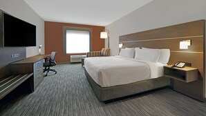 A hotel room with a large bed, a desk with a flat-screen TV, a chair, and a bedside table with a phone. - Holiday Inn Express Hotel & Suites NEWPORT by IHG (Newport)