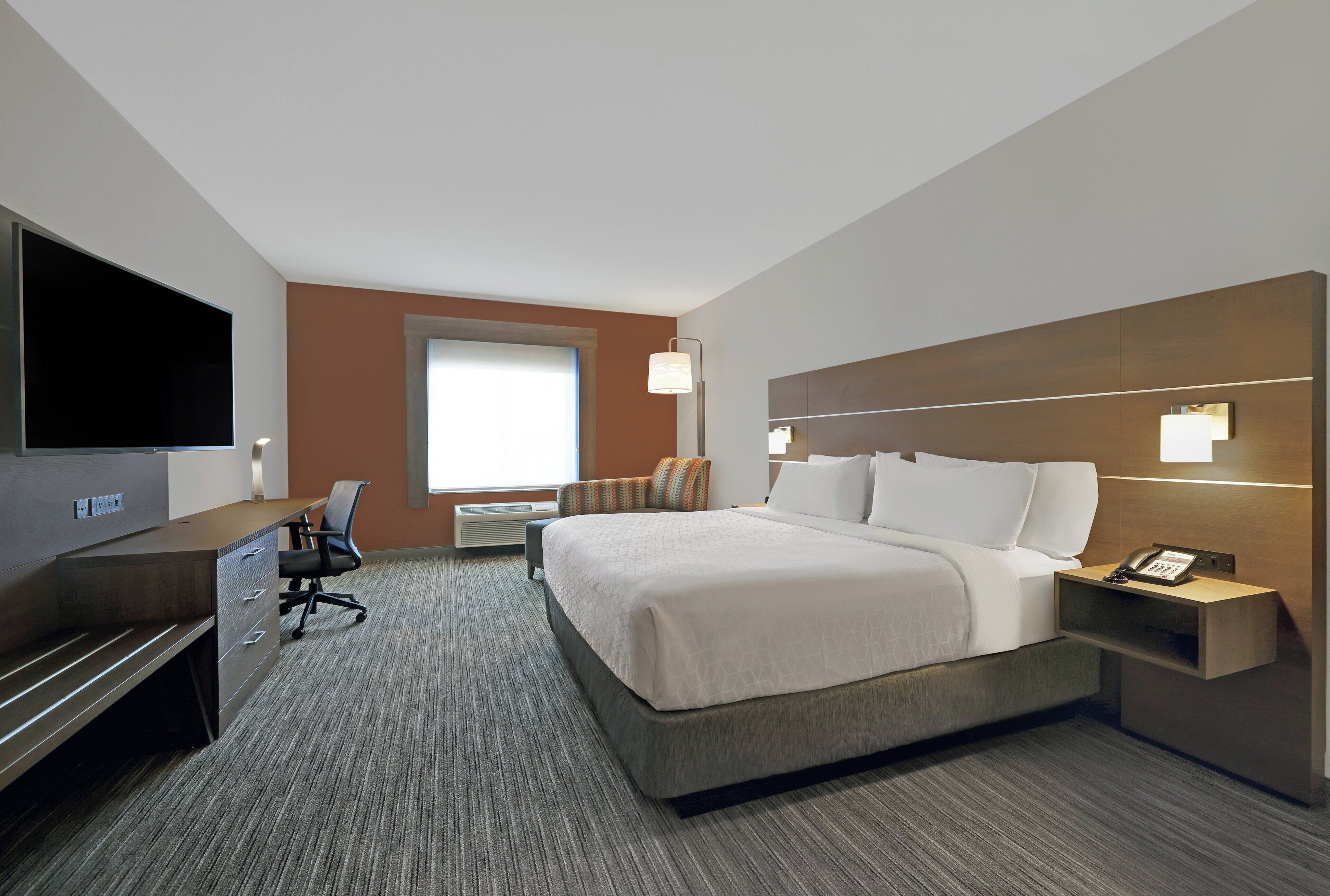 A hotel room with a bed, desk, chair, television, and a telephone.