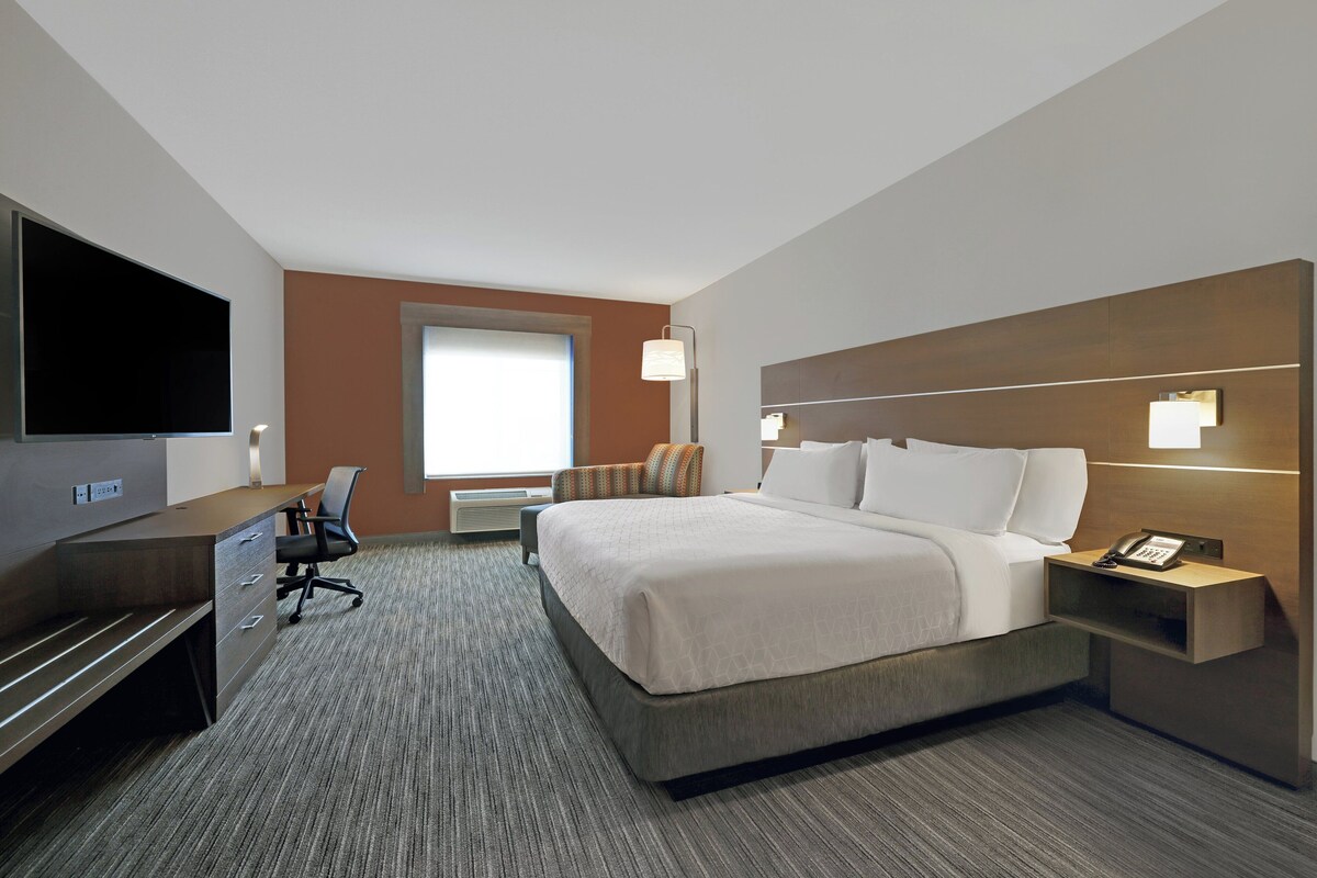 A hotel room with a bed, desk, chair, television, and a telephone.