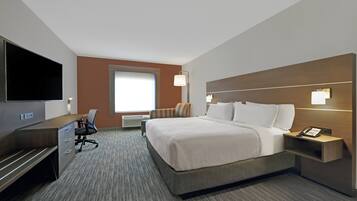 Una habitación de hotel con cama, escritorio, silla, televisor y teléfono.