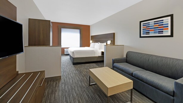 A hotel room with a bed, a sofa, a TV, a desk, and a painting on the wall. - Holiday Inn Express Hotel & Suites NEWPORT by IHG (Newport)