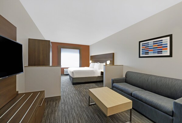 Hotelkamer met een bed, een bank, een televisie, een bureau en een schilderij aan de muur.