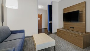 A modern hotel room with a sofa, a coffee table, a flat-screen TV, and a wooden cabinet. - Holiday Inn Express Hotel & Suites NEWPORT by IHG (Newport)