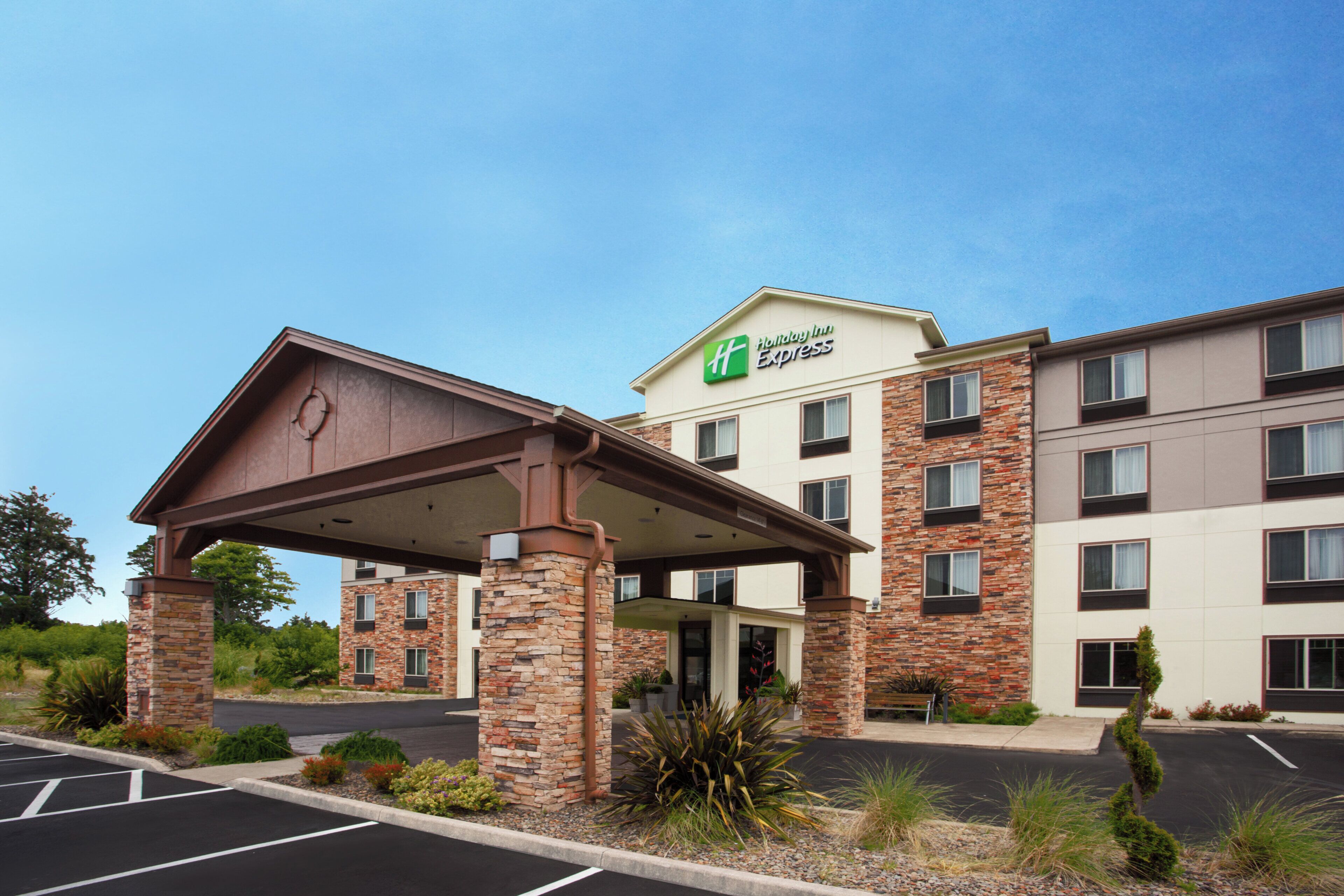 Un bâtiment de la chaîne Holiday Inn Express doté d’une entrée abritée, d’une façade en pierre et de nombreuses fenêtres.