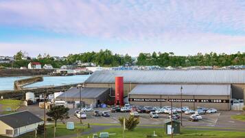 Un grand bâtiment industriel avec un parking à l’avant, une façade donnant sur le port et des immeubles résidentiels en arrière-plan.
