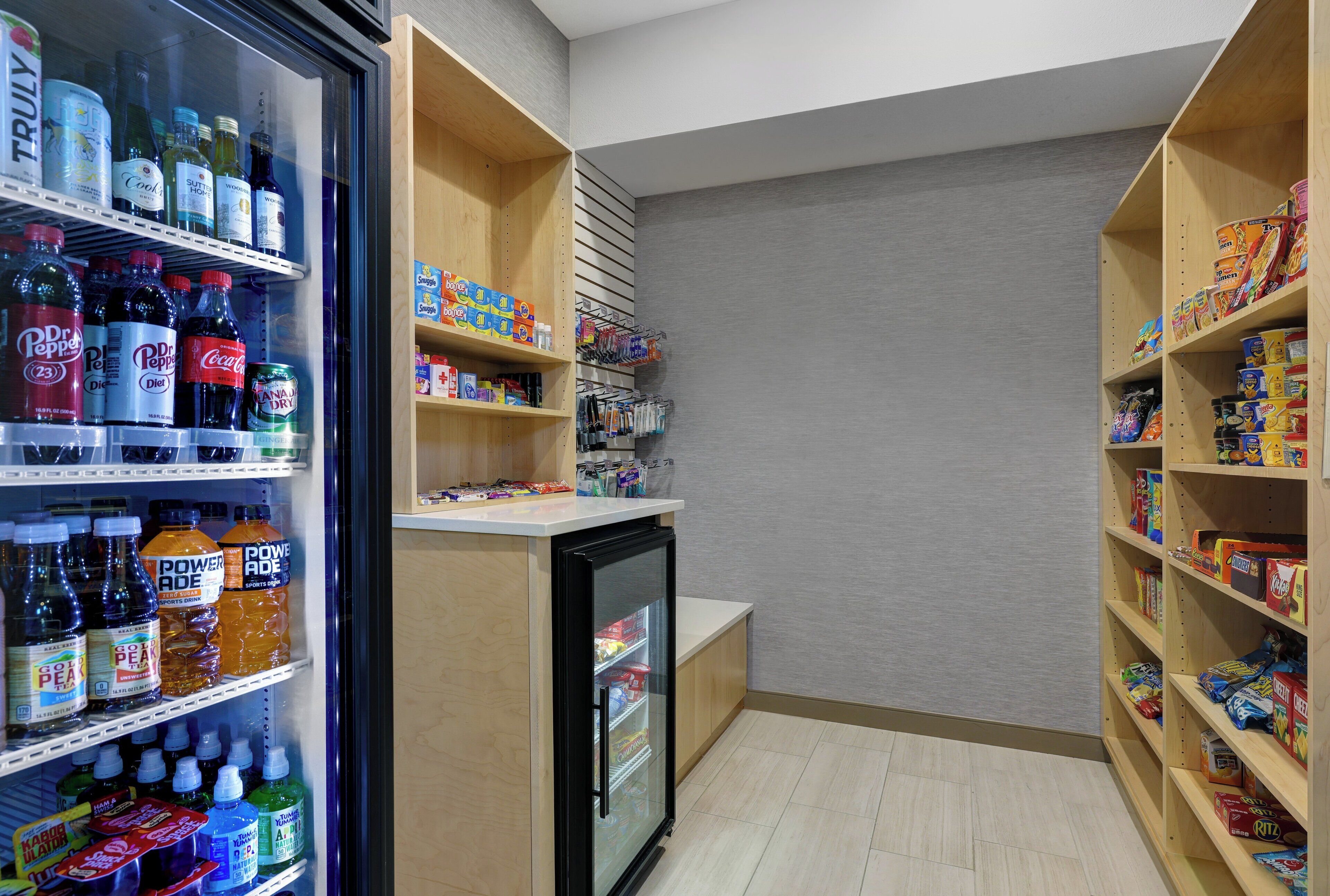A small, well-organized pantry with shelves stocked with beverages, snacks, and household items.