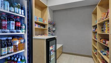 A small, well-organized pantry with shelves stocked with beverages, snacks, and household items.