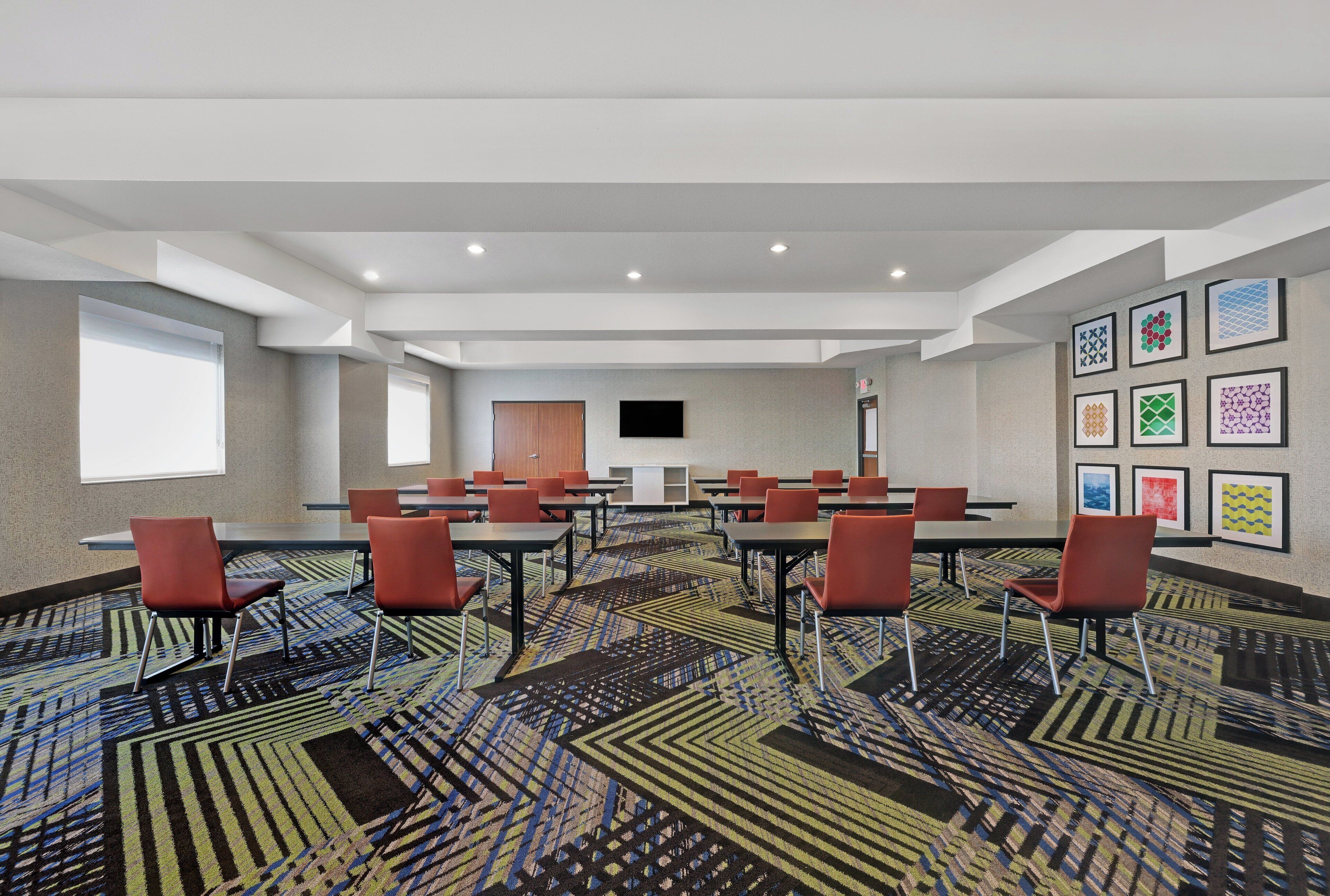 A conference room with tables, chairs, a TV, and framed artwork on the walls.