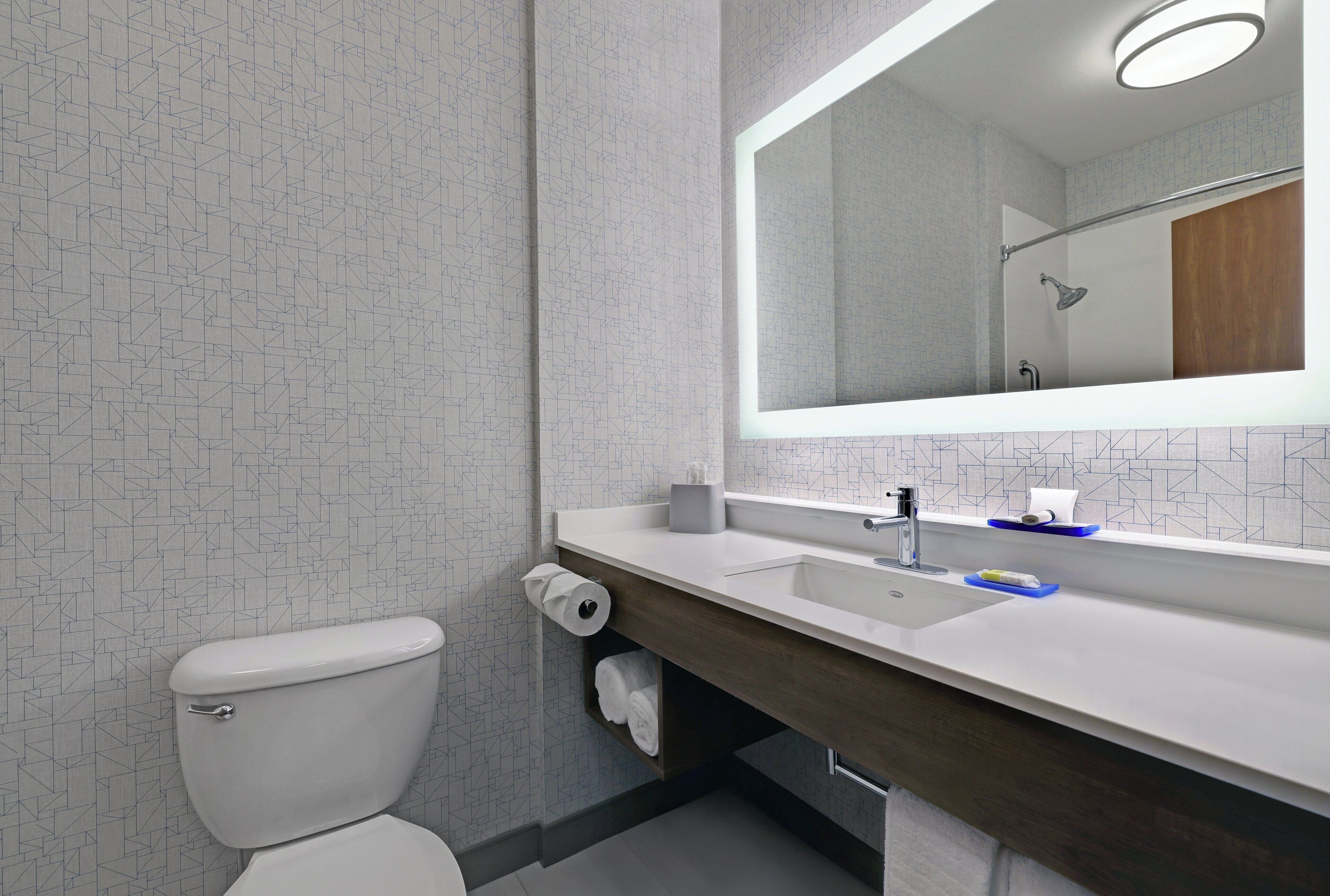 A modern bathroom with a toilet, sink, and mirror.