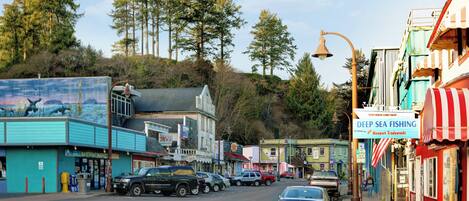 A coastal town street with buildings, parked cars, and a sign for 'Deep Sea Fishing'.