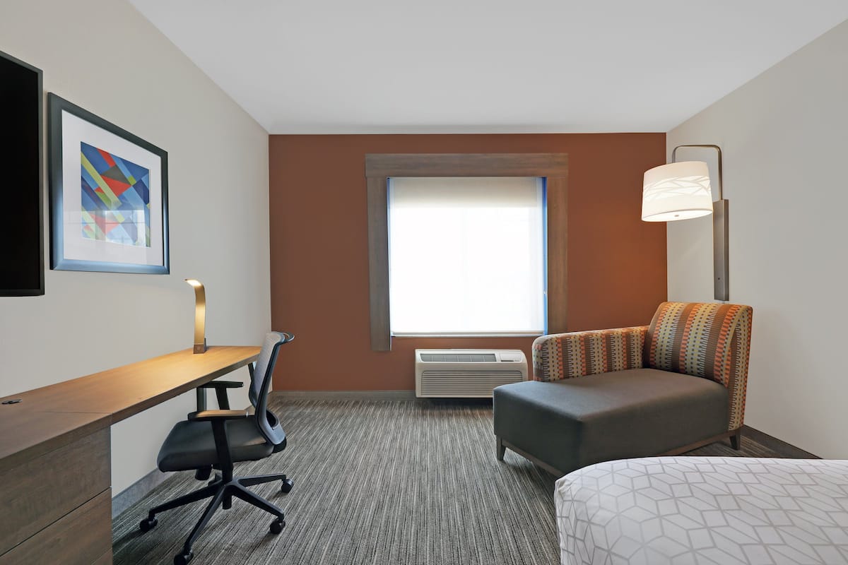A hotel room with a desk, chair, sofa, and a bed.