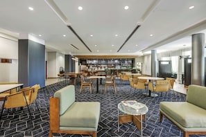 Un'hall dell'hotel con aree salotto, un bar e una zona ristorazione.