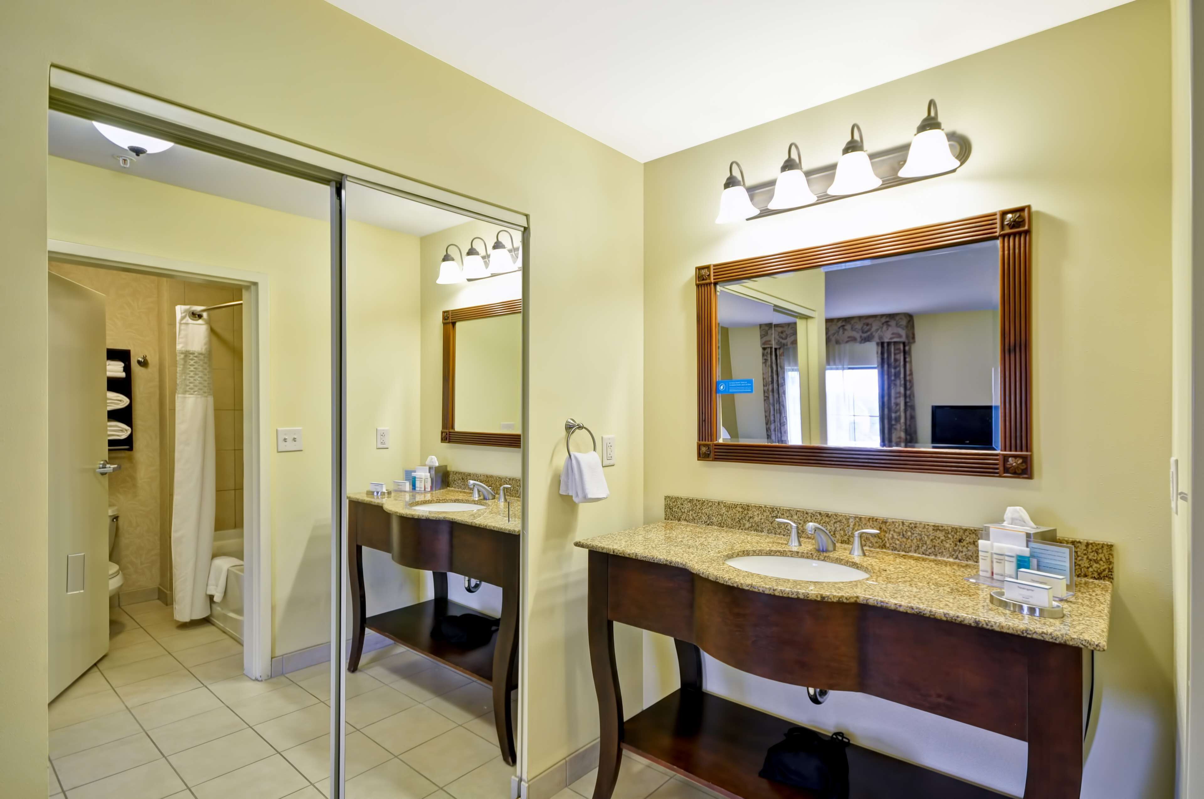 A bathroom with two sinks, a large mirror, and a shower area.