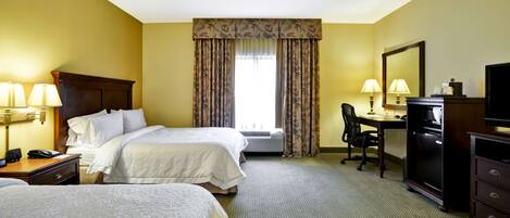 A hotel room with two beds, a desk, a chair, a television, and a mirror.
