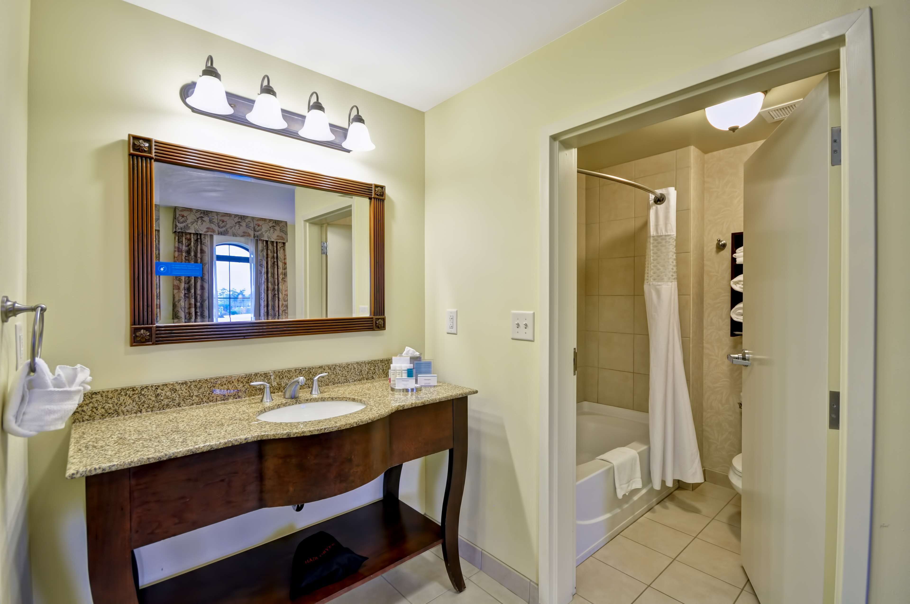 Baño con tocador, lavabo y espejo. Cuenta con zona de ducha con cortina y bañera.