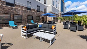 An outdoor patio with a sectional sofa, lounge chairs, and umbrellas.
