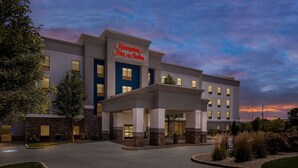 A Hampton Inn & Suites building with a modern architectural design, featuring a prominent entrance and a well-lit facade.