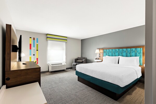 Une chambre d’hôtel avec un lit, un bureau, une chaise, une télévision et une fenêtre.