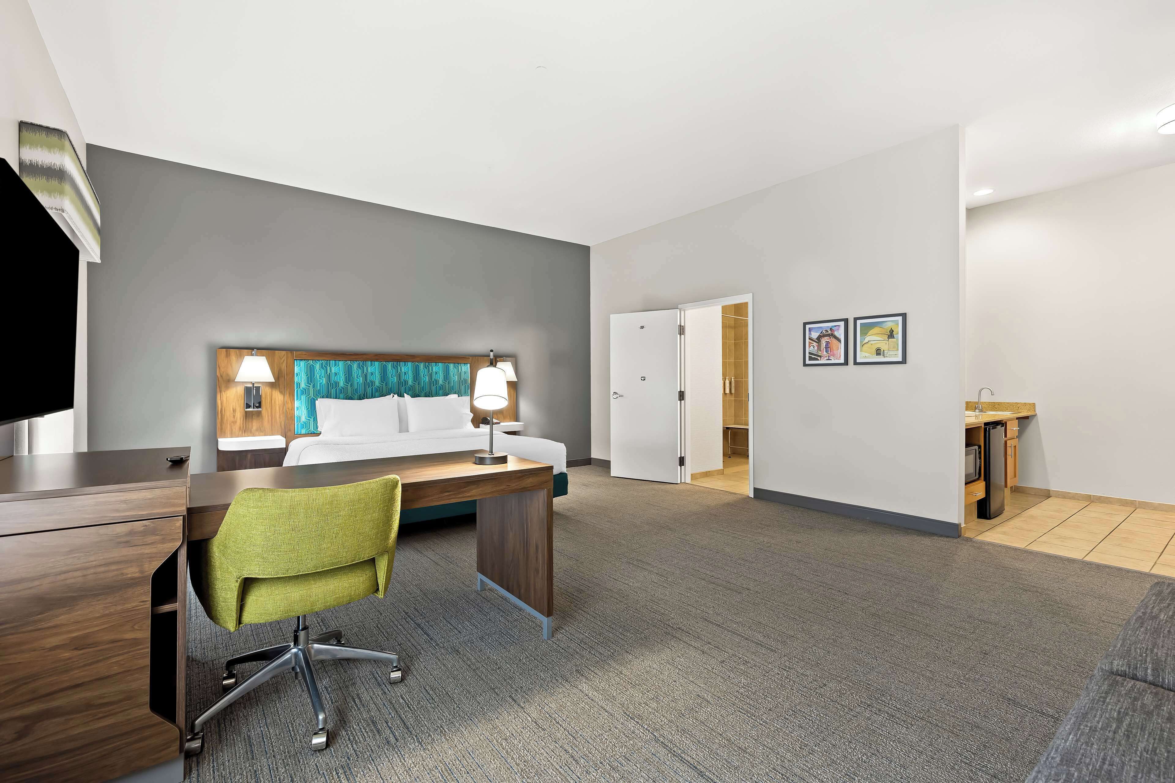 Une chambre d’hôtel équipée d’un lit, d’un bureau, d’une chaise et d’un coin cuisine.
