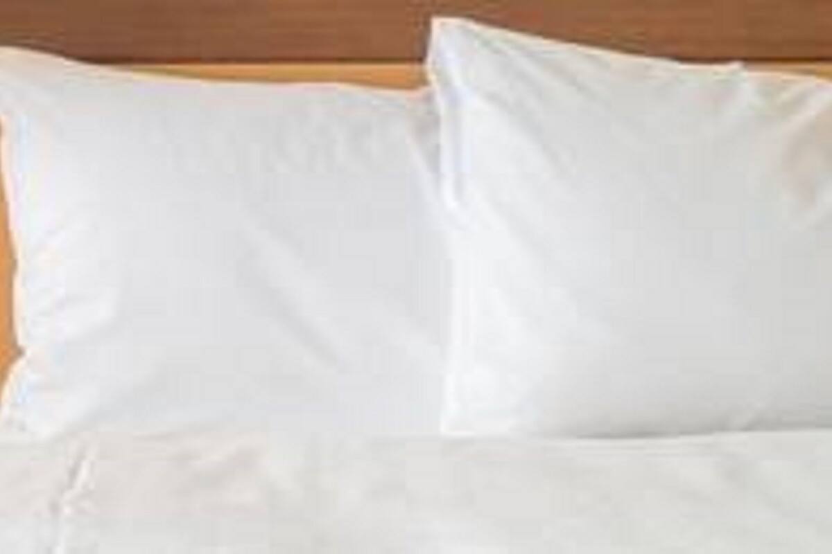 A bed with white bedding and a wooden headboard.