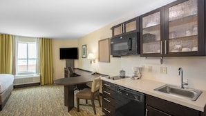 Une chambre d’hôtel équipée d’une kitchenette, d’un lit, d’un bureau et d’une télévision.