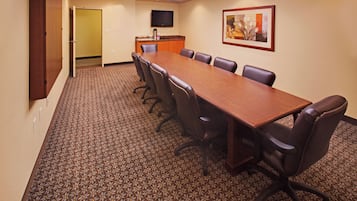 A conference room with a long table, chairs, a flat-screen TV, and a framed picture on the wall.