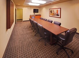 A conference room with a long table, chairs, a flat-screen TV, and a framed picture on the wall.