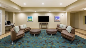 Habitación de hotel con un televisor de pantalla plana grande, dos sofás, una mesa de centro y piso alfombrado.