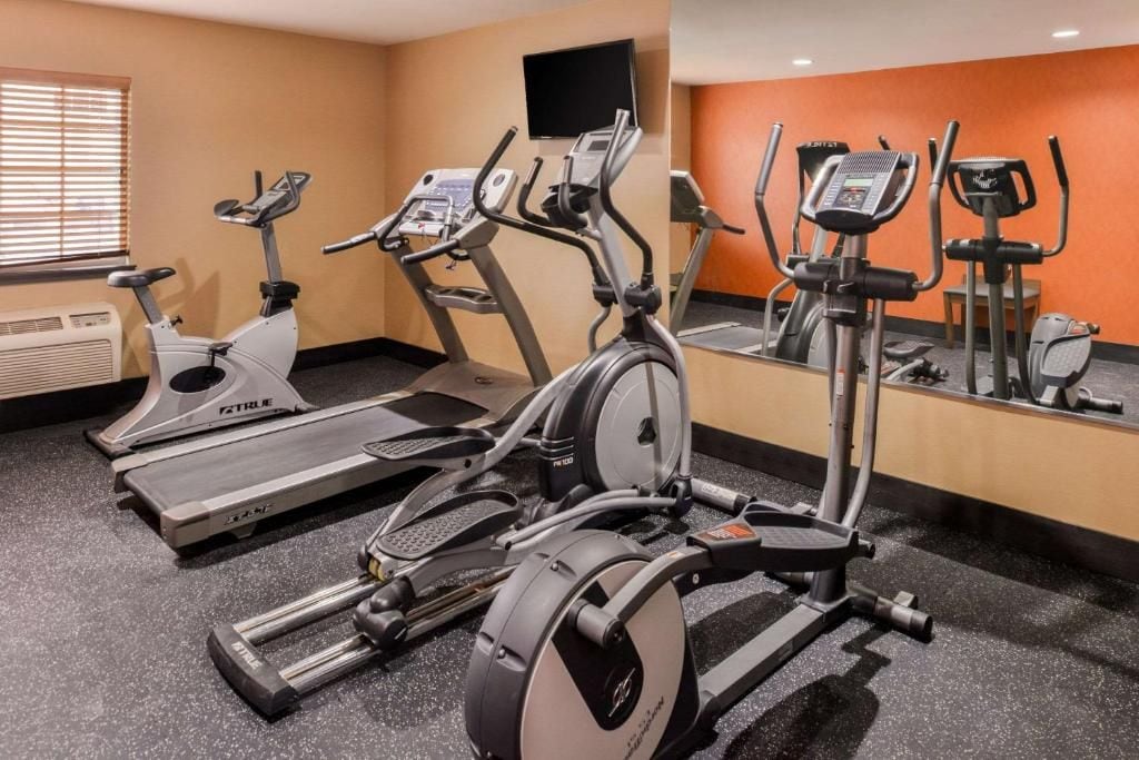 A gym with treadmills, elliptical machines, and a mirrored wall.