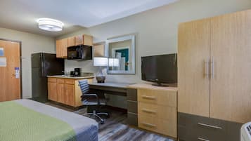 Habitación de hotel con cama, escritorio con computadora, televisión, microondas y refrigerador.