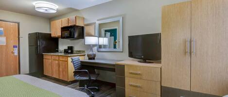 Habitación de hotel con cama, escritorio con computadora, televisión, microondas y refrigerador.
