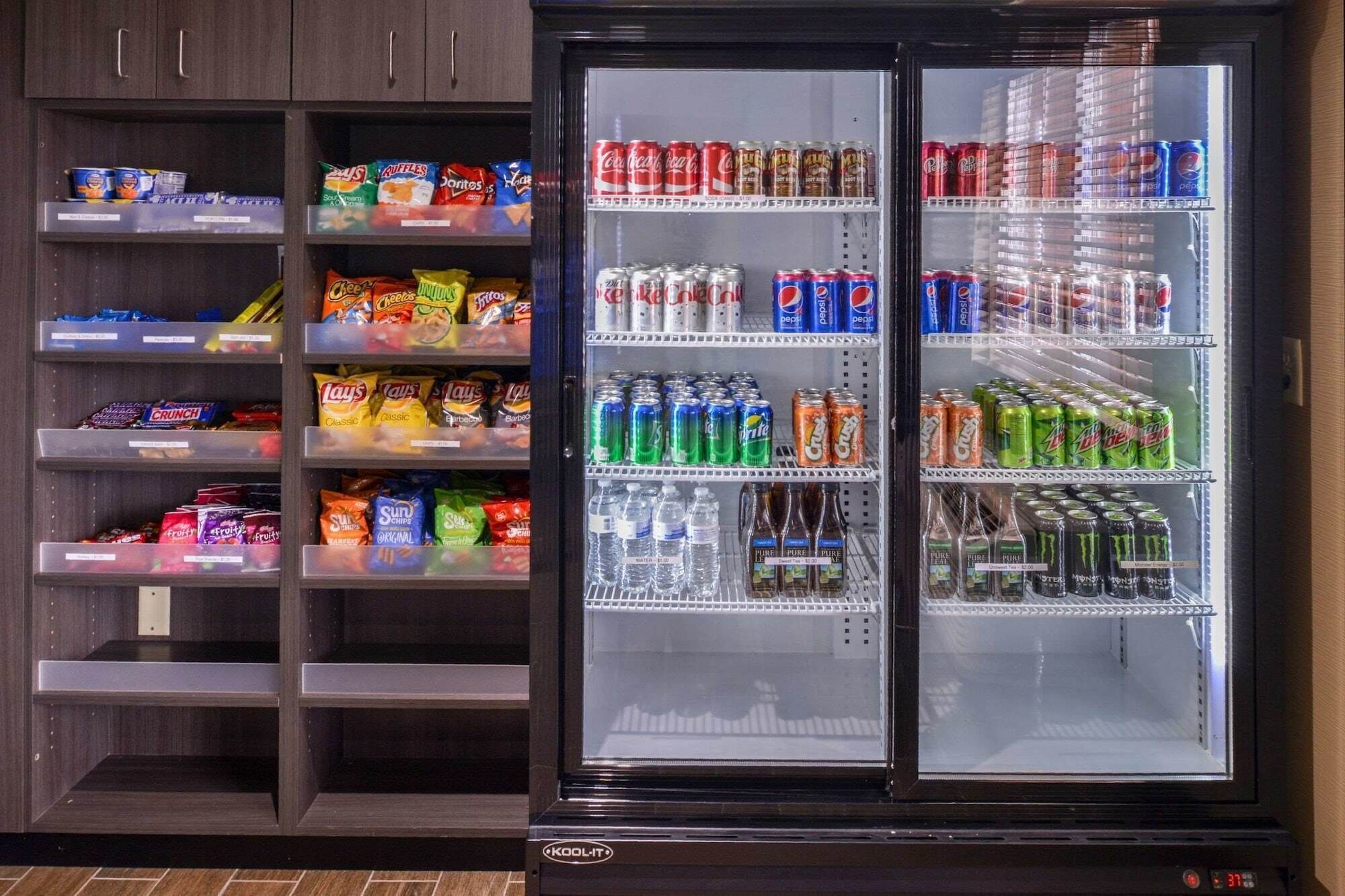 Máquina expendedora llena de aperitivos y bebidas, incluyendo papas fritas, refrescos y agua embotellada.