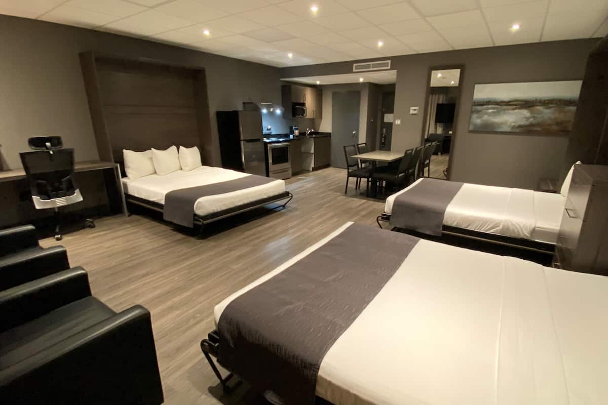 Une chambre d’hôtel avec deux lits, un bureau, une chaise, une machine à café et un téléviseur.