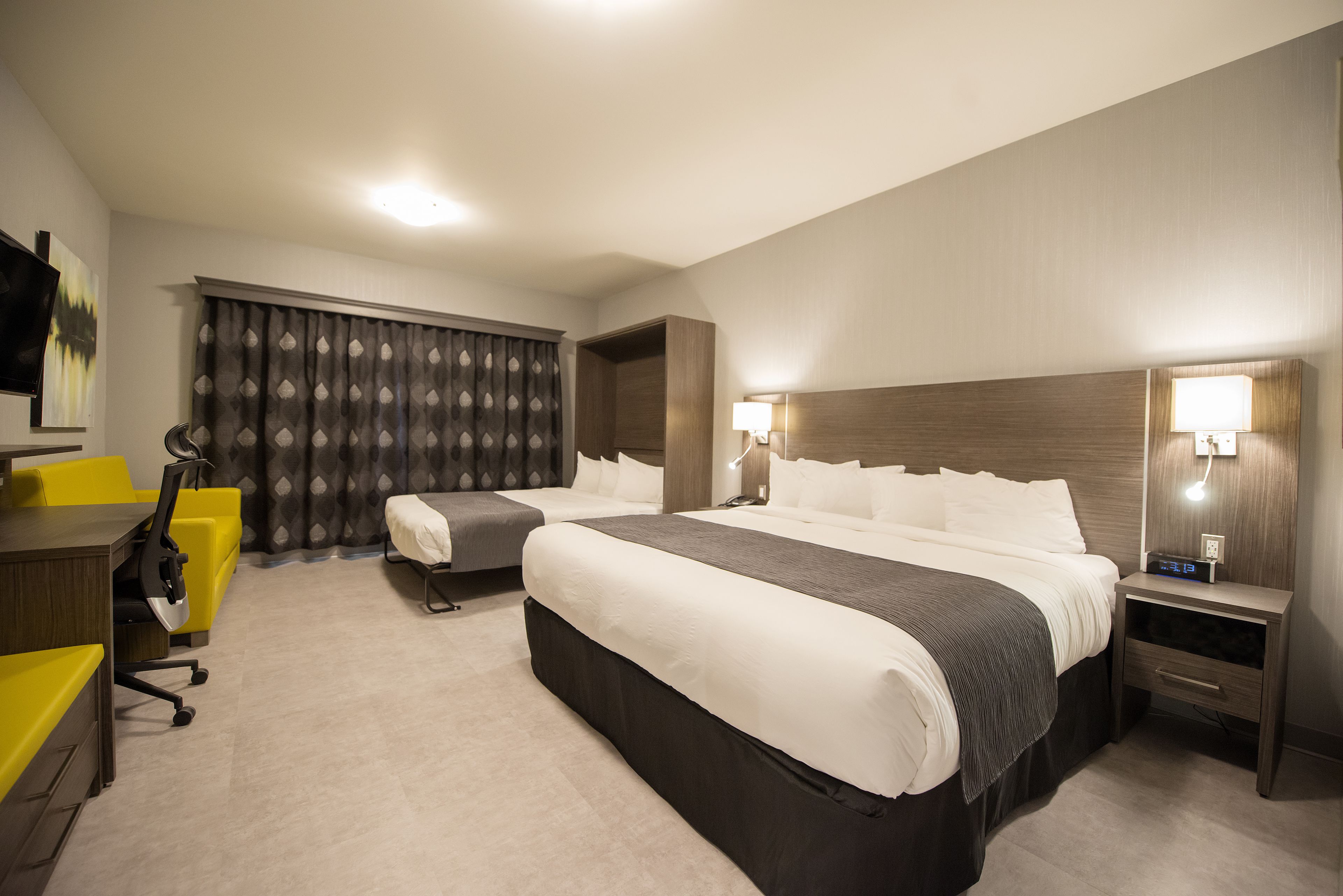 A hotel room with two beds, a desk, and a chair.