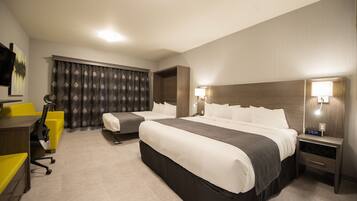 A hotel room with two beds, a desk, and a chair.